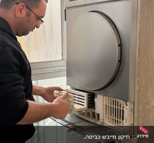 אדם מתקן מכונת כביסה עם מייבש